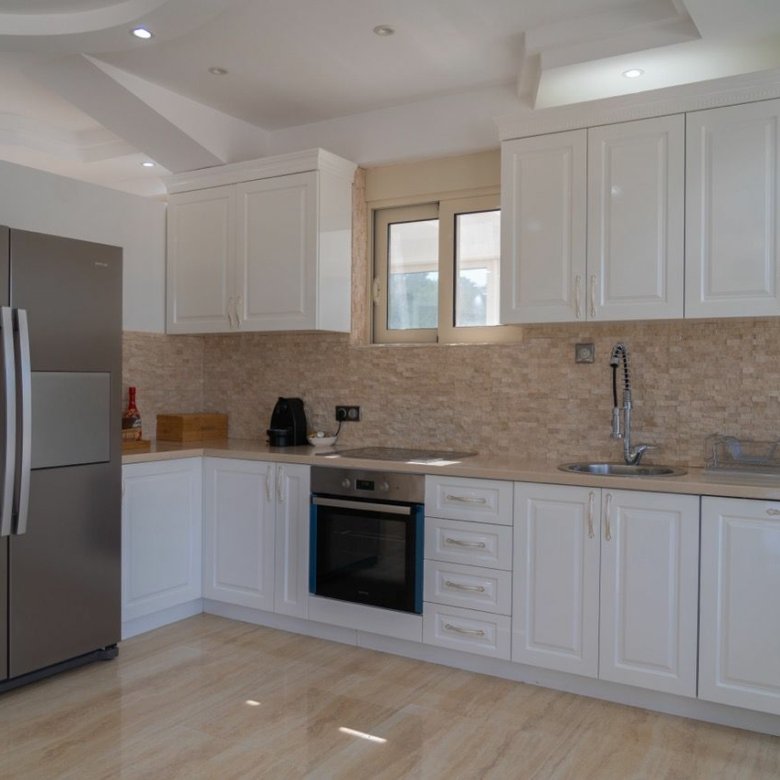 Stunning Ulcinj kitchen: sleek white cabinets, tiled backsplash, stainless appliances. Invest in Montenegro real estate with Ekosphere.