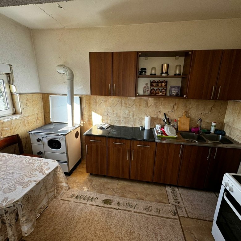 Modern Ulcinj kitchen with brown cabinets, black countertop, wood stove; sunlit eco property&mdash;investment at immorenta.me (ekosphere doo).