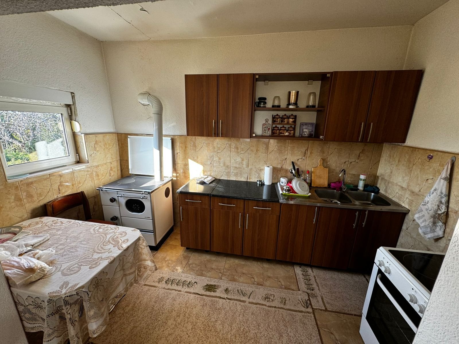 Modern Ulcinj kitchen with brown cabinets, black countertop, wood stove; sunlit eco property&mdash;investment at immorenta.me (ekosphere doo).