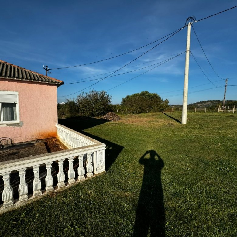 Beautiful Ulcinj property: lush lawn, pink house with white railing, patio, and trees. Exclusive at immorenta.me by ekosphere doo.