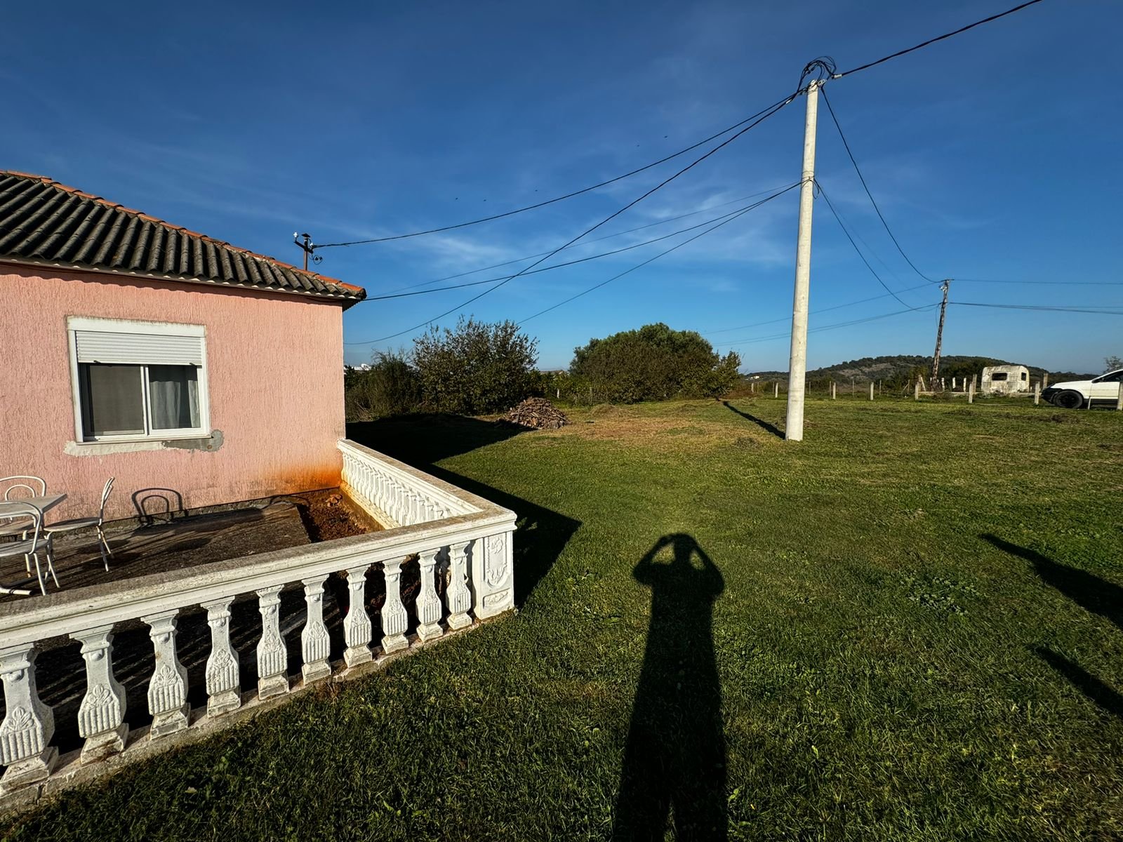 Beautiful Ulcinj property: lush lawn, pink house with white railing, patio, and trees. Exclusive at immorenta.me by ekosphere doo.