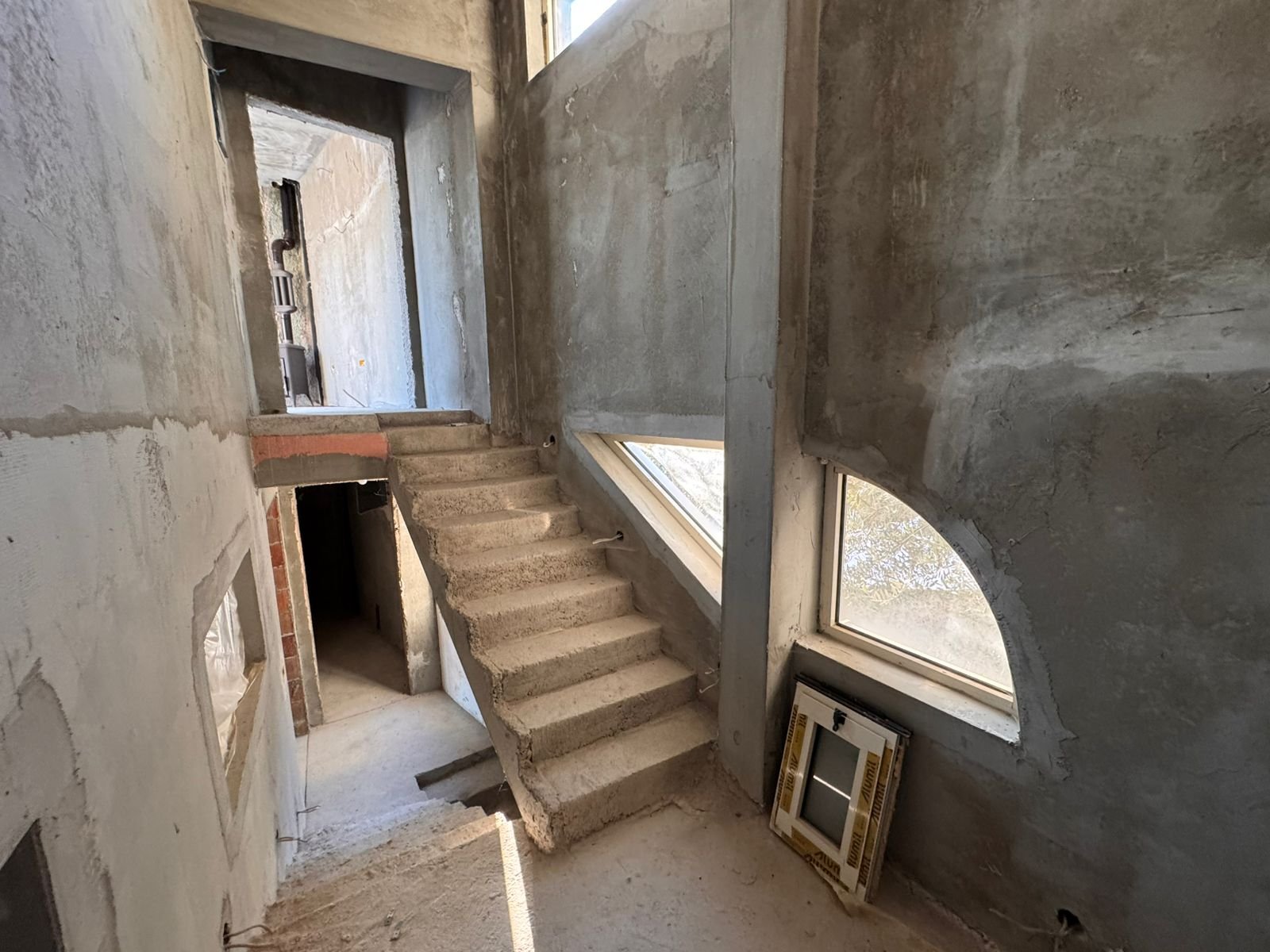 Spacious unfinished interior in Ulcinj, Montenegro with concrete stairs and arched windows&mdash;prime investment via immorenta.me by Ekosphere doo.