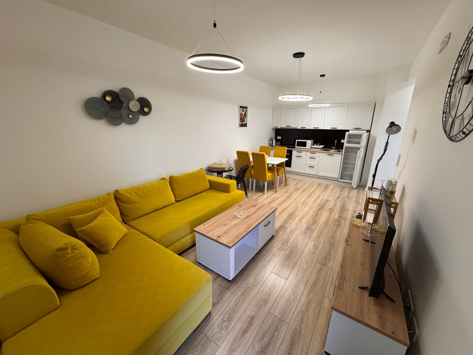 Stylish Ulcinj living room with yellow sofa, wood table, and dining area&mdash;an exclusive ekosphere doo property on immorenta.me.
