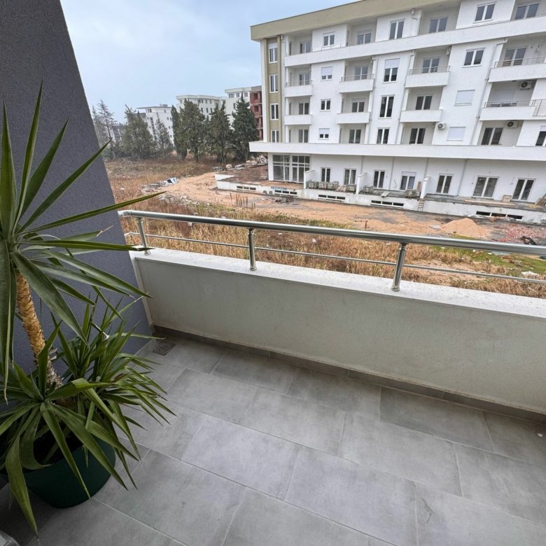 Modern balcony with gray tiles and railing, overlooks new Ulcinj apartments&mdash;prime real estate by ekosphere doo at immorenta.me.