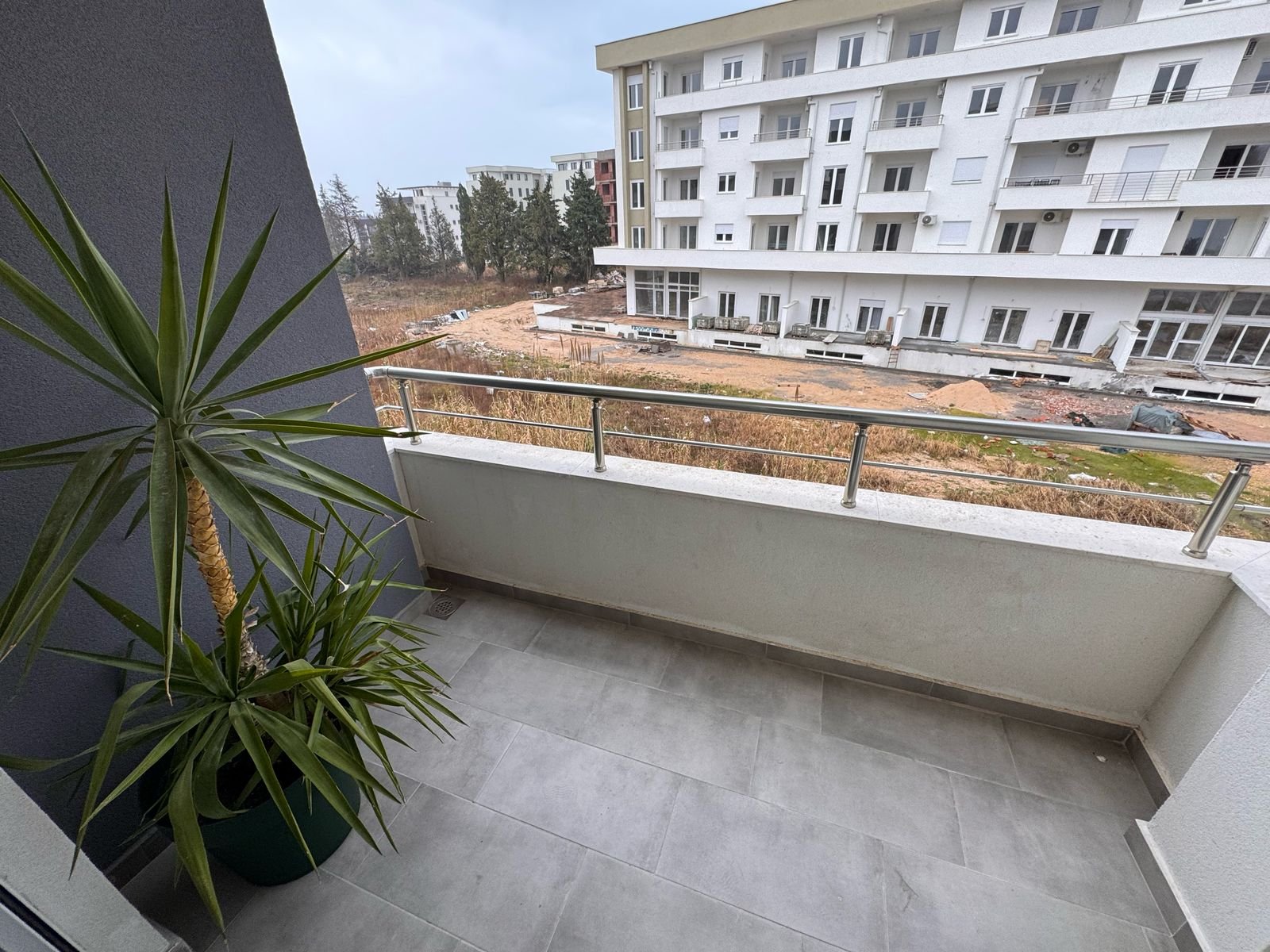 Modern balcony with gray tiles and railing, overlooks new Ulcinj apartments&mdash;prime real estate by ekosphere doo at immorenta.me.