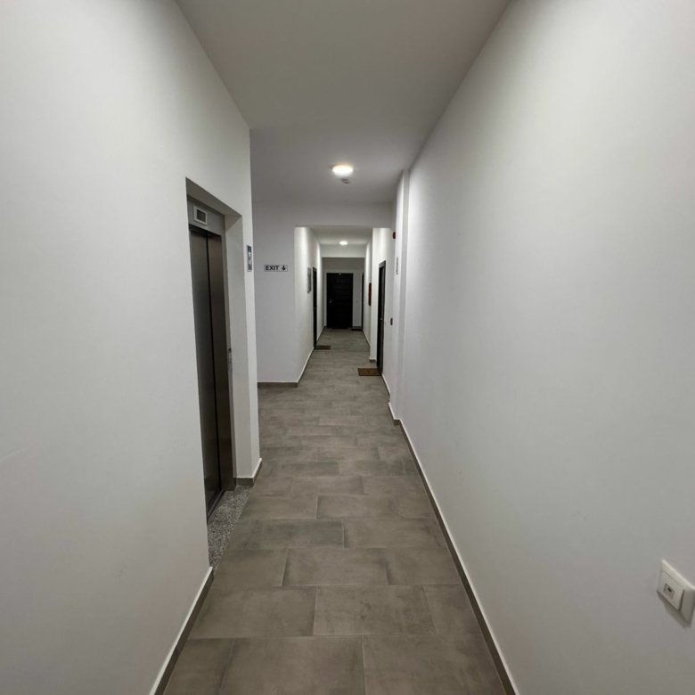 Modern hallway with elevator, pristine white walls, and quality gray tiles&mdash;perfect Ulcinj real estate. A immorenta.me project by ekosphere doo.