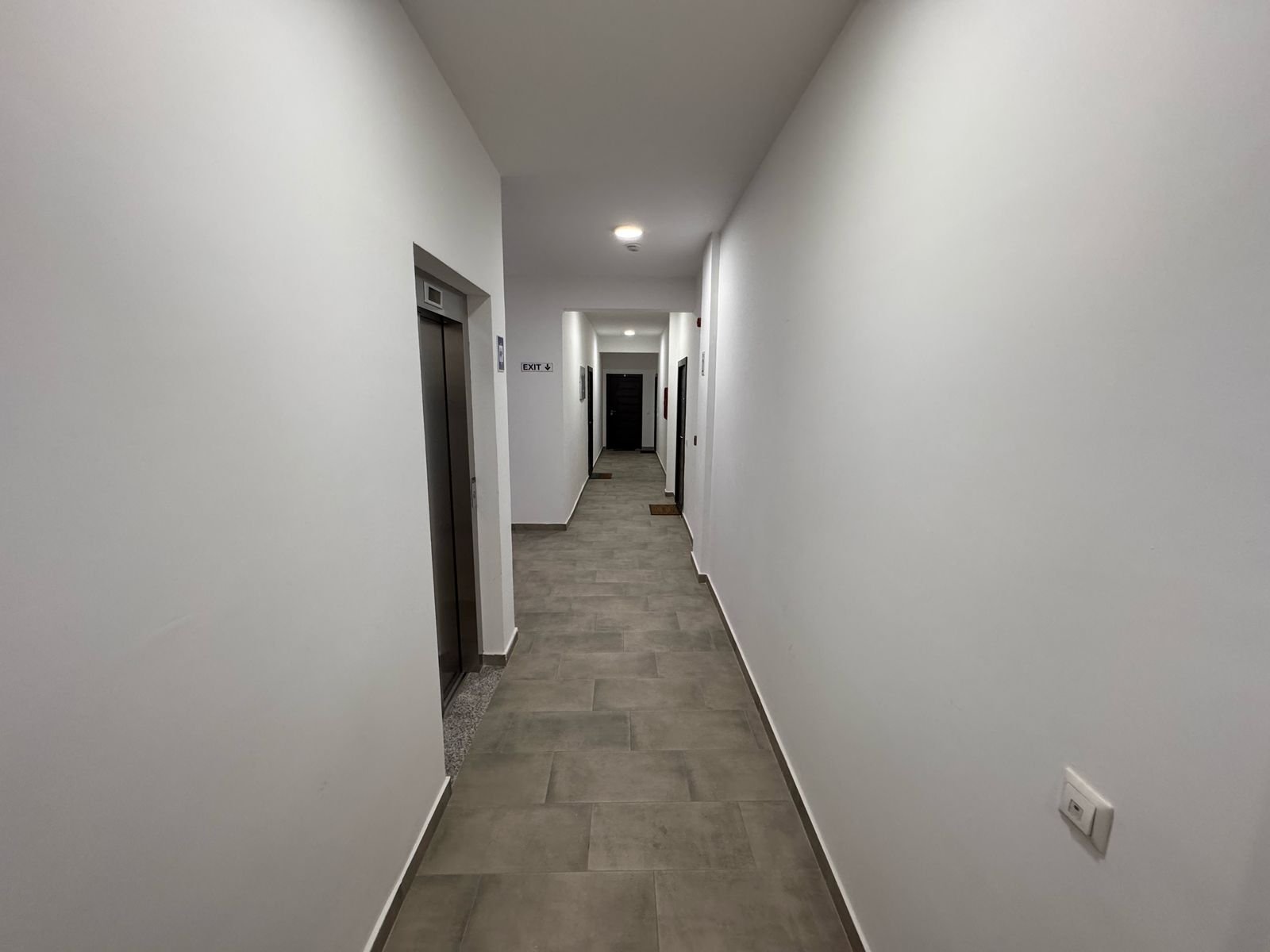Modern hallway with elevator, pristine white walls, and quality gray tiles&mdash;perfect Ulcinj real estate. A immorenta.me project by ekosphere doo.