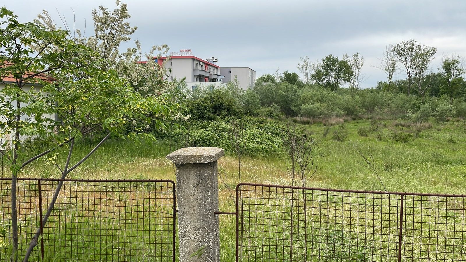 Prime Ulcinj, Montenegro property: lush field, scenic views, modern home with red roof&mdash;exclusive at immorenta.me by Ekosphere doo.