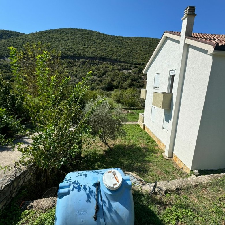 Charming white house with red roof, water tank, lush greenery, hills&mdash;prime Ulcinj real estate by ekosphere doo on immorenta.me.