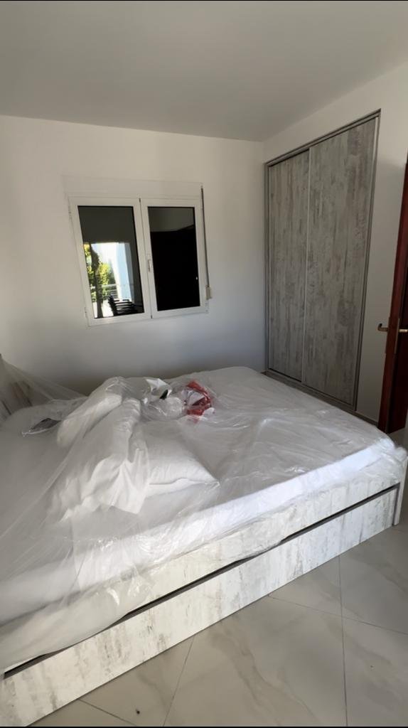 Spacious Ulcinj bedroom with tiled floors, large white bed, ample wardrobe, bright window&mdash;ideal Montenegro investment by ekosphere doo.