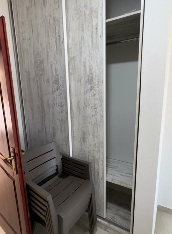 Modern wood-finish wardrobe, light tiled floors, and stacked chairs enhance this Ulcinj property&mdash;exclusive with immorenta.me by ekosphere doo.