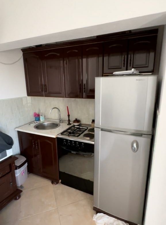 Modern kitchen in Ulcinj property: sleek dark cabinets, stainless fridge, gas stove. Invest via immorenta.me by ekosphere doo.