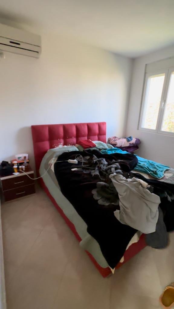 Modern Ulcinj bedroom with red tufted headboard, natural light, AC unit; top Montenegro property at immorenta.me by Ekosphere.