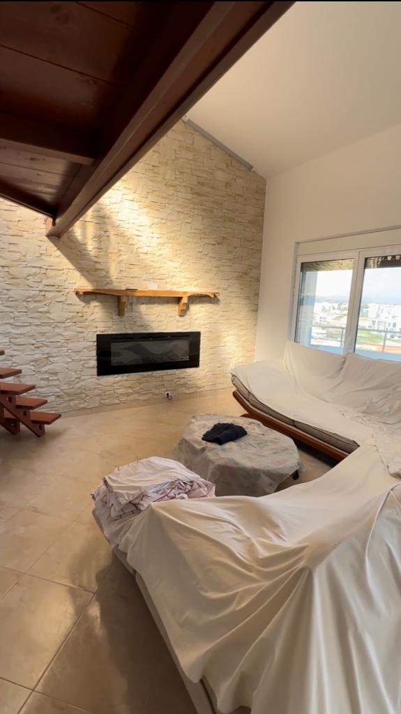 Elegant Ulcinj living room with stone walls, modern fireplace, and luxe sofas&mdash;prime Montenegro real estate by Ekosphere doo.