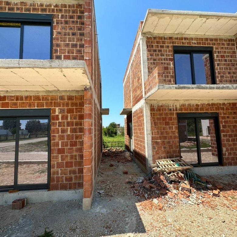 Prime Ulcinj investment: two unfinished brick homes with glass features, ideal for custom development. Listed by Ekosphere on immorenta.me.