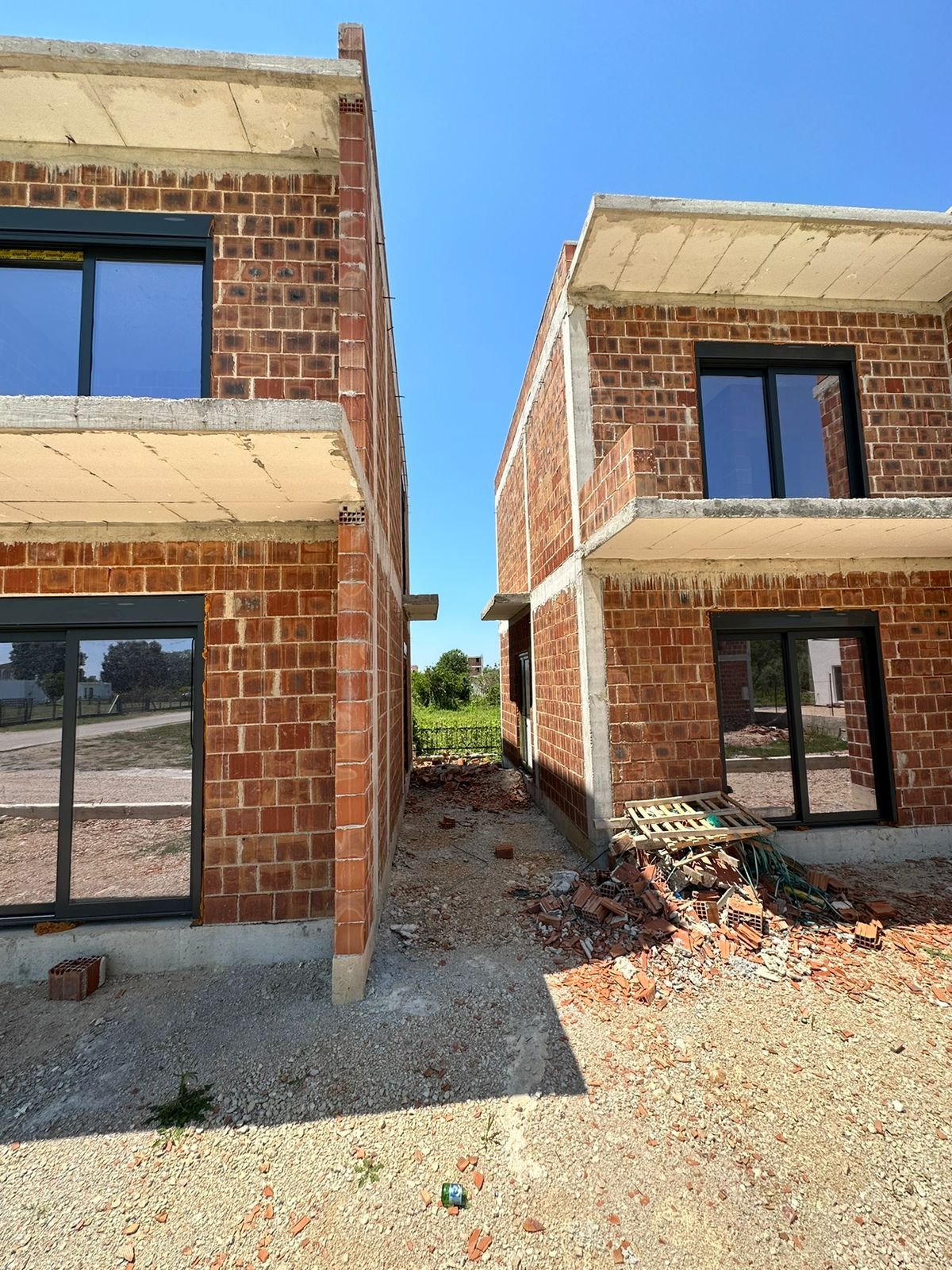 Prime Ulcinj investment: two unfinished brick homes with glass features, ideal for custom development. Listed by Ekosphere on immorenta.me.