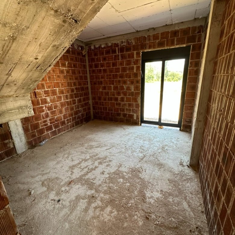 Spacious unfinished Ulcinj property with brick walls, concrete floor, and bright glass door&mdash;prime investment by ekosphere doo.