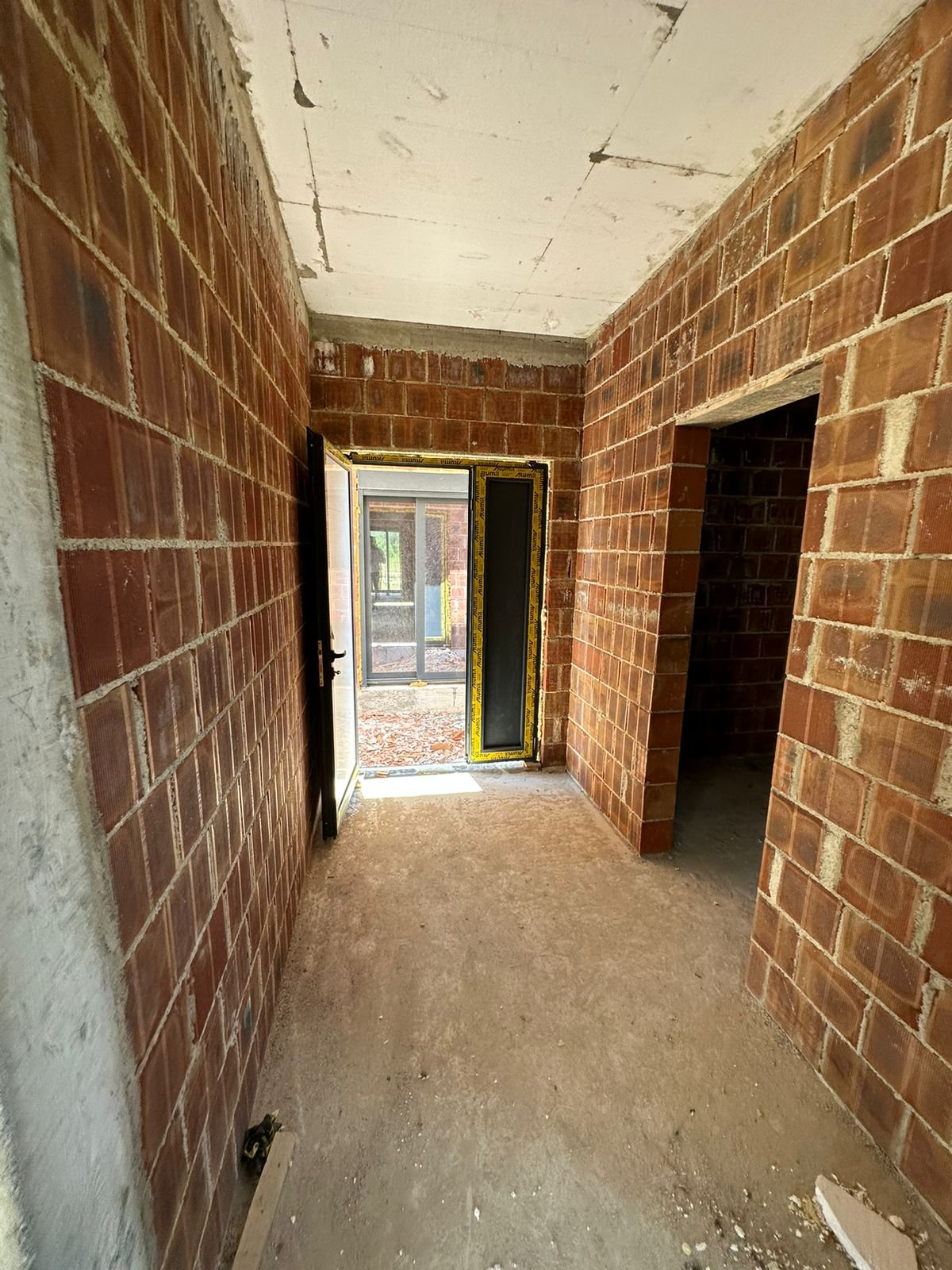 Bright, unfinished red brick space with dual open doorways&mdash;prime Ulcinj investment listed by immorenta.me (ekosphere doo).