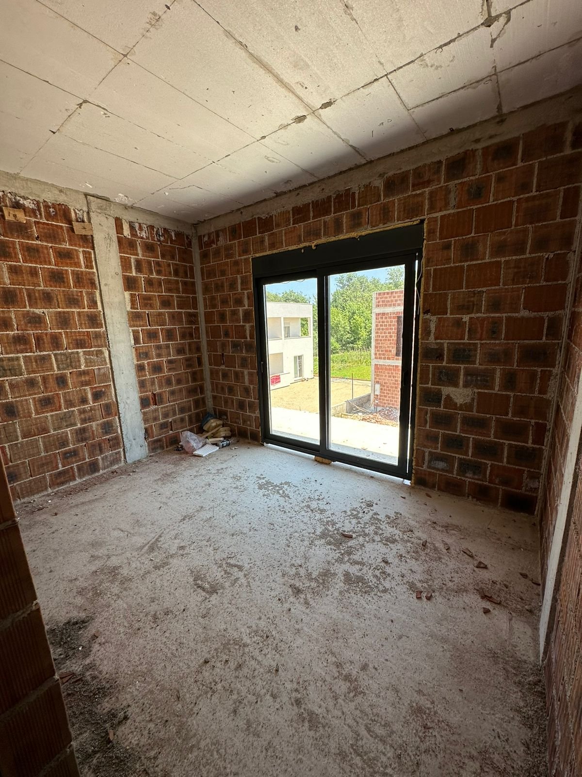 Unfinished room with brick walls, concrete ceiling, and wide glass doors overlooking Ulcinj&rsquo;s property market&mdash;exclusive by Ekosphere, immorenta.me.