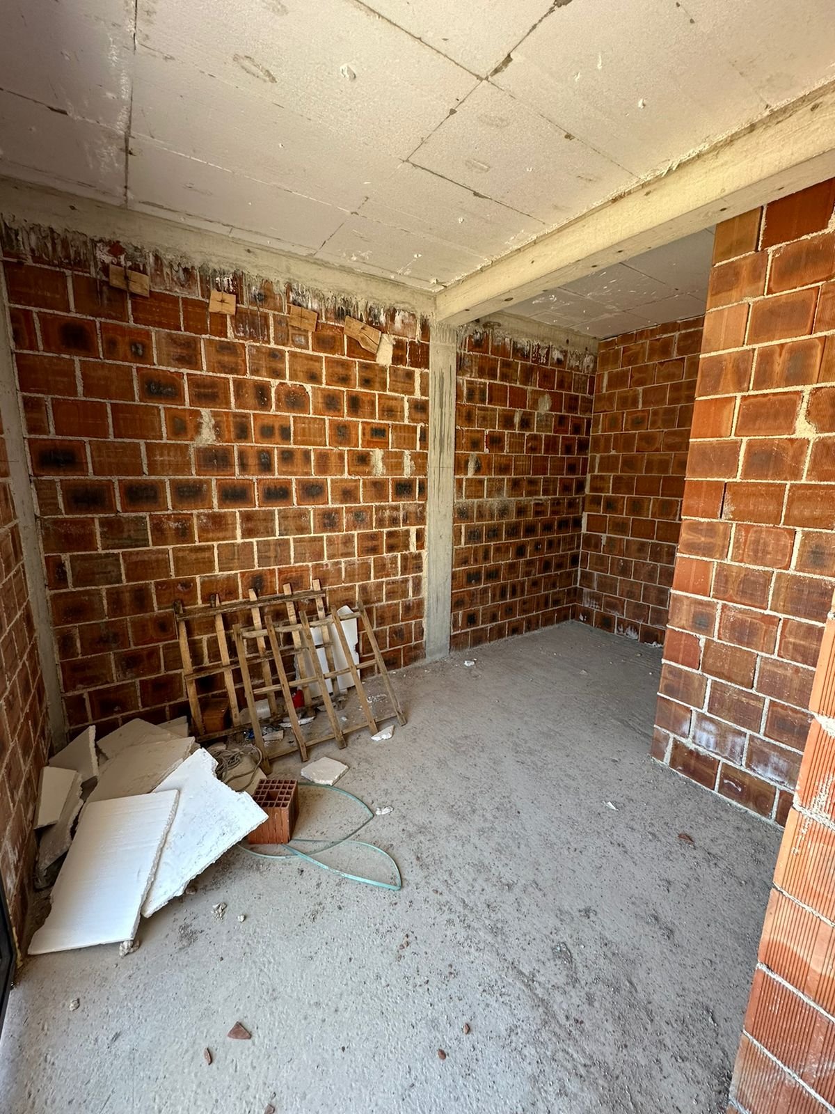 Prime investment opportunity in Ulcinj: spacious unfinished room with brick walls, concrete floor, and renovation potential. Montenegro-listings.me by ekosphere doo.