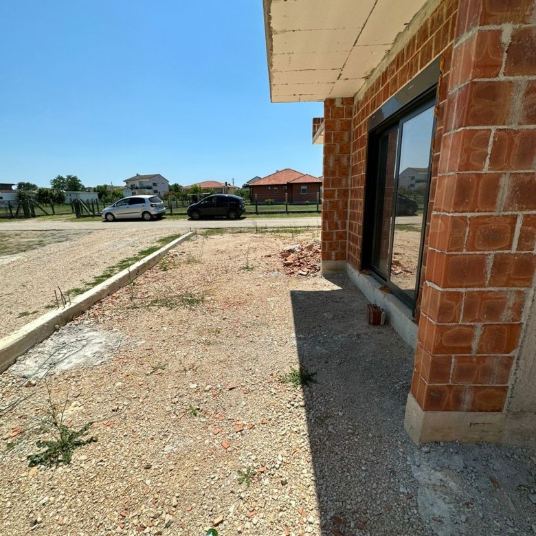 Modern brick building by Ekosphere with glass doors, gravel yard, and Ulcinj real estate views&mdash;exclusive at immorenta.me.