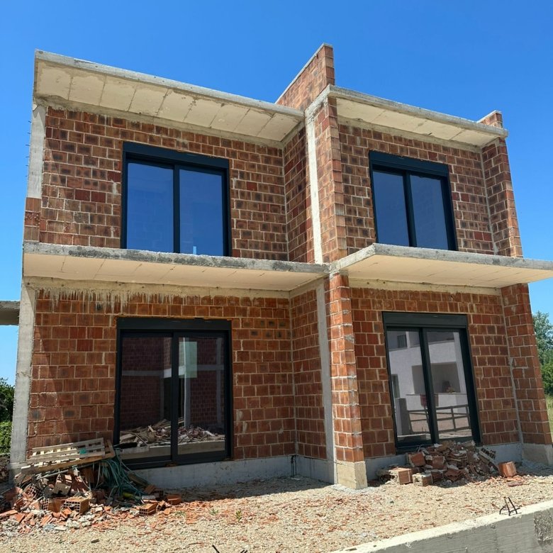 Modern two-story house under construction in Ulcinj, Montenegro&mdash;prime real estate with brick walls, large windows, and investment potential. Montenegro-listings.me by Ekosphere DOO.
