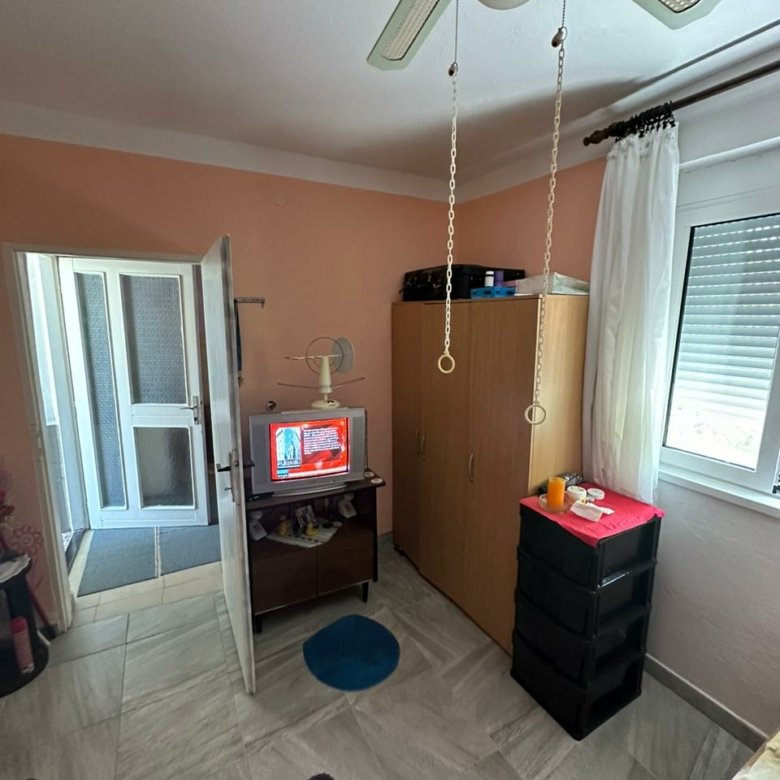 Modern Ulcinj room with tiled floors, ceiling fan, wardrobe, and TV. Prime real estate by Ekosphere DOO on immorenta.me.