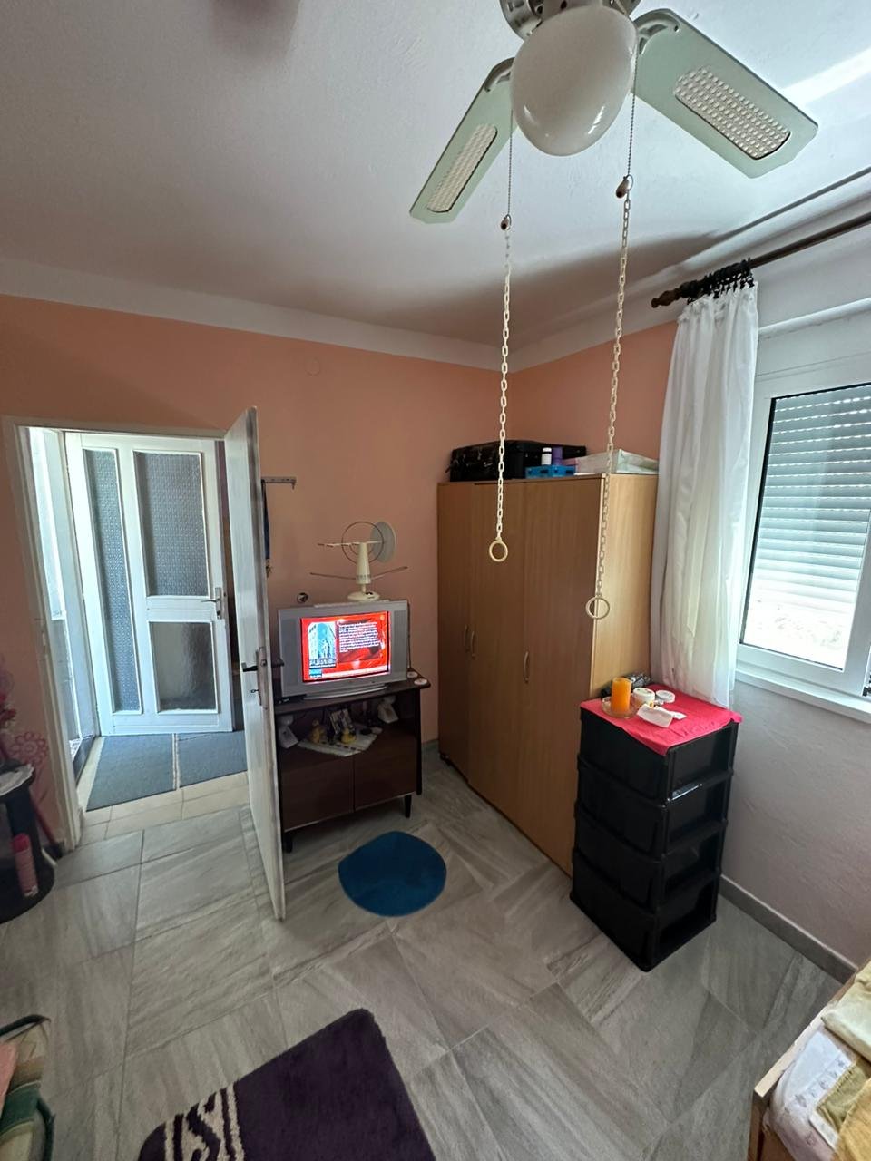 Modern Ulcinj room with tiled floors, ceiling fan, wardrobe, and TV. Prime real estate by Ekosphere DOO on immorenta.me.