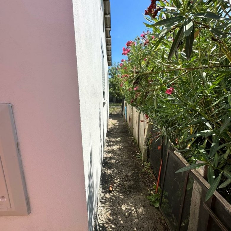 Charming walkway by a modern white building, lush gardens, and secure fencing&mdash;prime Ulcinj real estate via immorenta.me by ekosphere doo.