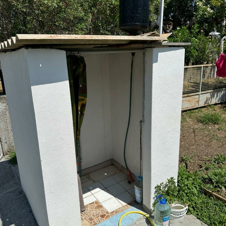 Modern outdoor shower with white walls, tiled floor, eco water tank&mdash;ideal Ulcinj property investment. By ekosphere doo on immorenta.me.