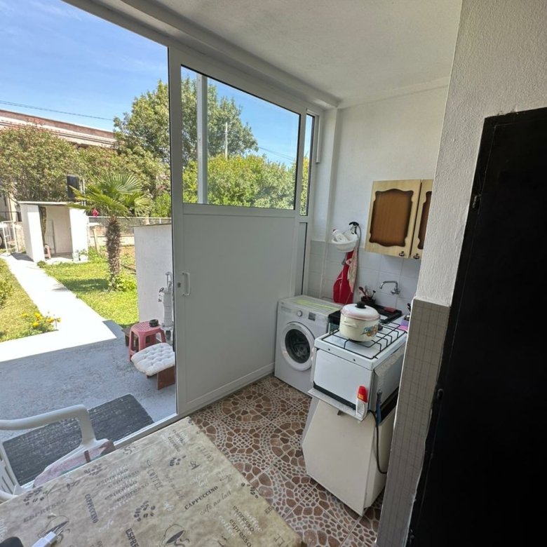 Modern Ulcinj laundry area with washer, stove, tiled floors, glass garden door&mdash;ideal eco-investment at immorenta.me by Ekosphere.