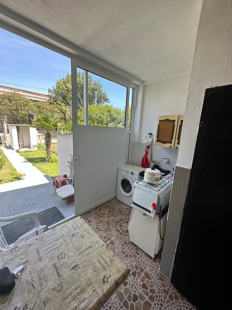 Modern Ulcinj laundry area with washer, stove, tiled floors, glass garden door&mdash;ideal eco-investment at immorenta.me by Ekosphere.
