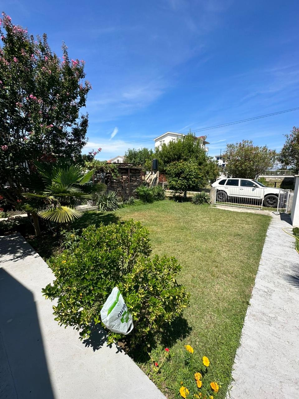 Discover this Ulcinj Montenegro property: lush lawn, mature trees, gated access, and prime curb appeal. Invest via immorenta.me by ekosphere doo.