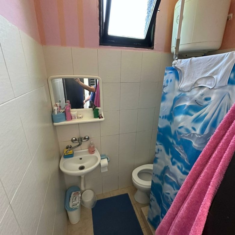 Bright bathroom in Ulcinj property: white tiles, sink with mirror, shower, window. Invest via immorenta.me by Ekosphere doo.