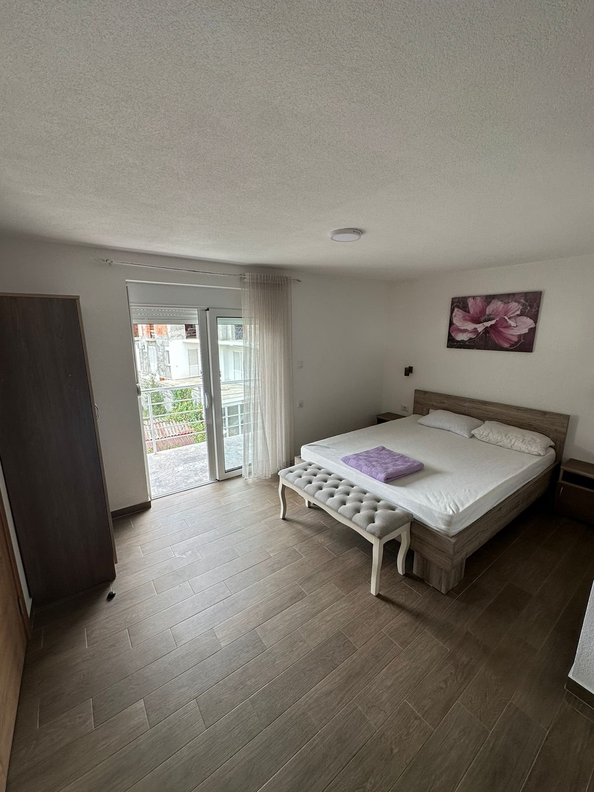 Luxury Ulcinj bedroom with double bed, bench, wardrobe, and bright window. Invest in Montenegro real estate&mdash;Ecosphere quality by immorenta.me.