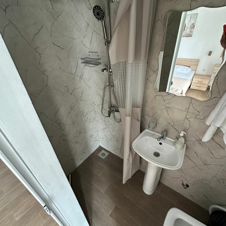 Modern bathroom in Ekosphere&rsquo;s Ulcinj property: rainfall shower, elegant sink, quality fixtures&mdash;ideal real estate investment.