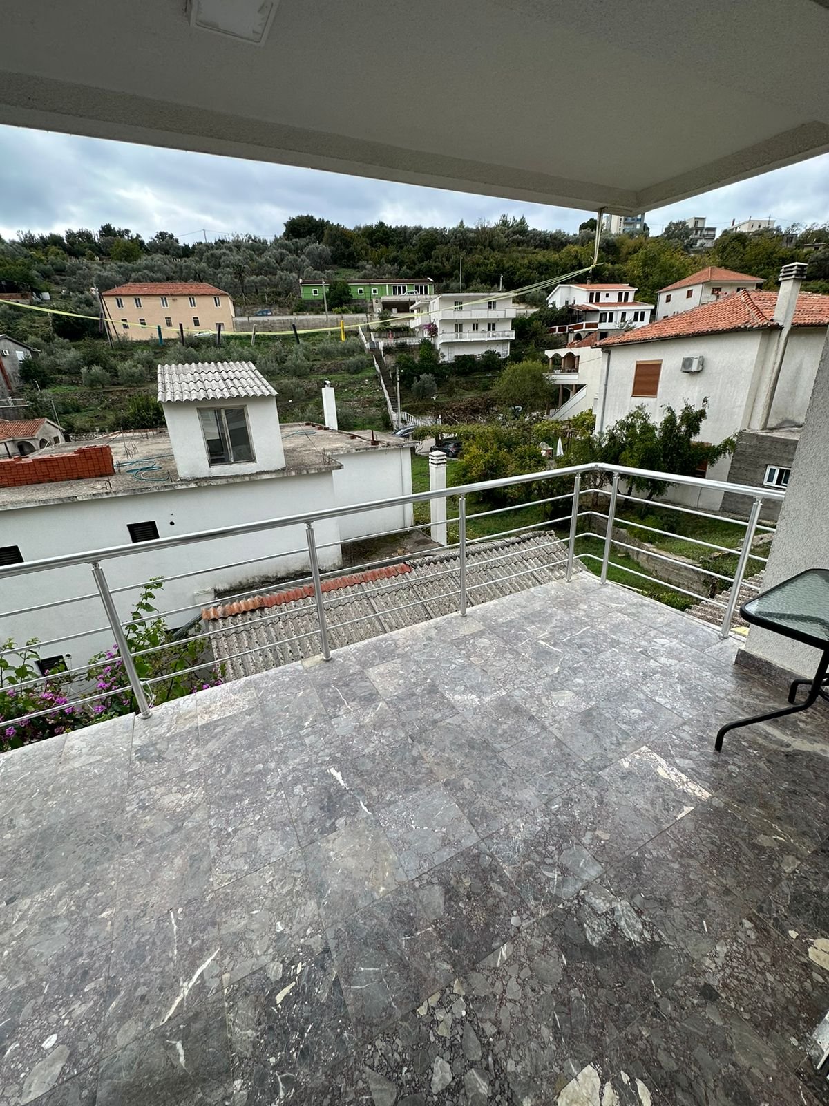 Spacious tiled balcony in Ulcinj with metal railing, glass table, lush views&mdash;ideal for investors. Featured on immorenta.me by ekosphere doo.