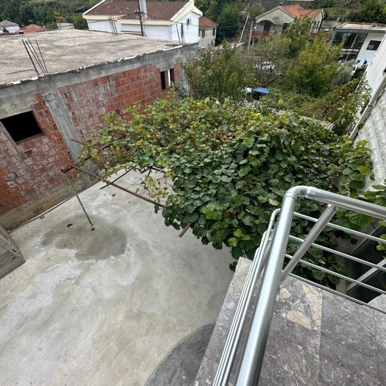 Stunning Ulcinj property view: balcony overlooks vine trellis, concrete yard, ekosphere homes in scenic hills. Invest at immorenta.me.