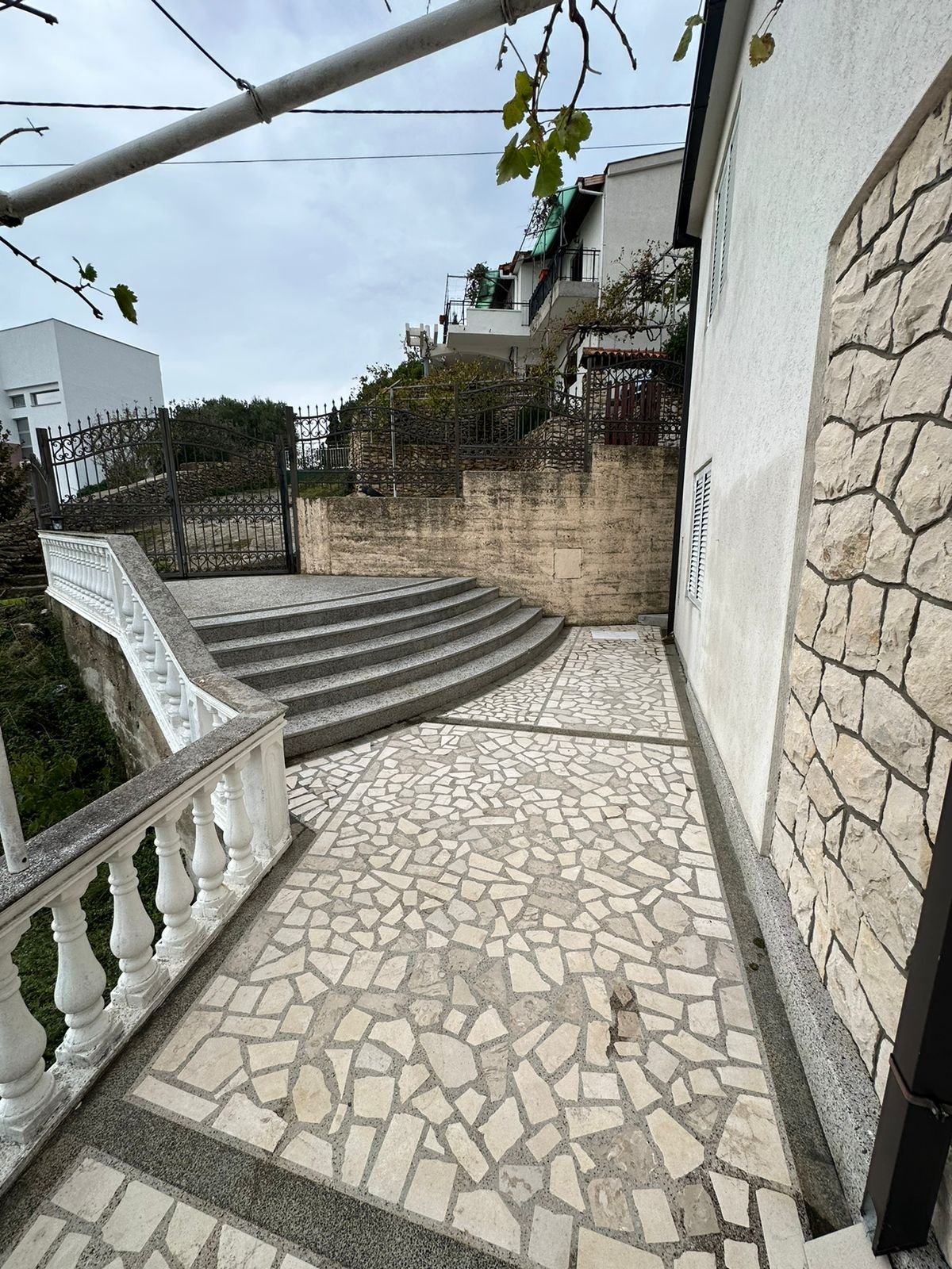 Elegant stone patio with balustrade, curved steps, and refined white fa&ccedil;ade&mdash;prime Ulcinj real estate by Ekosphere on immorenta.me.