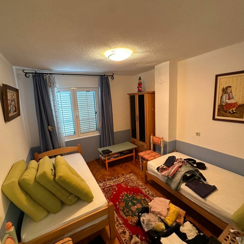 Charming Ulcinj bedroom with 2 single beds, wardrobe, red rug, blue curtains&mdash;ideal Montenegro real estate at immorenta.me by Ekosphere DOO.