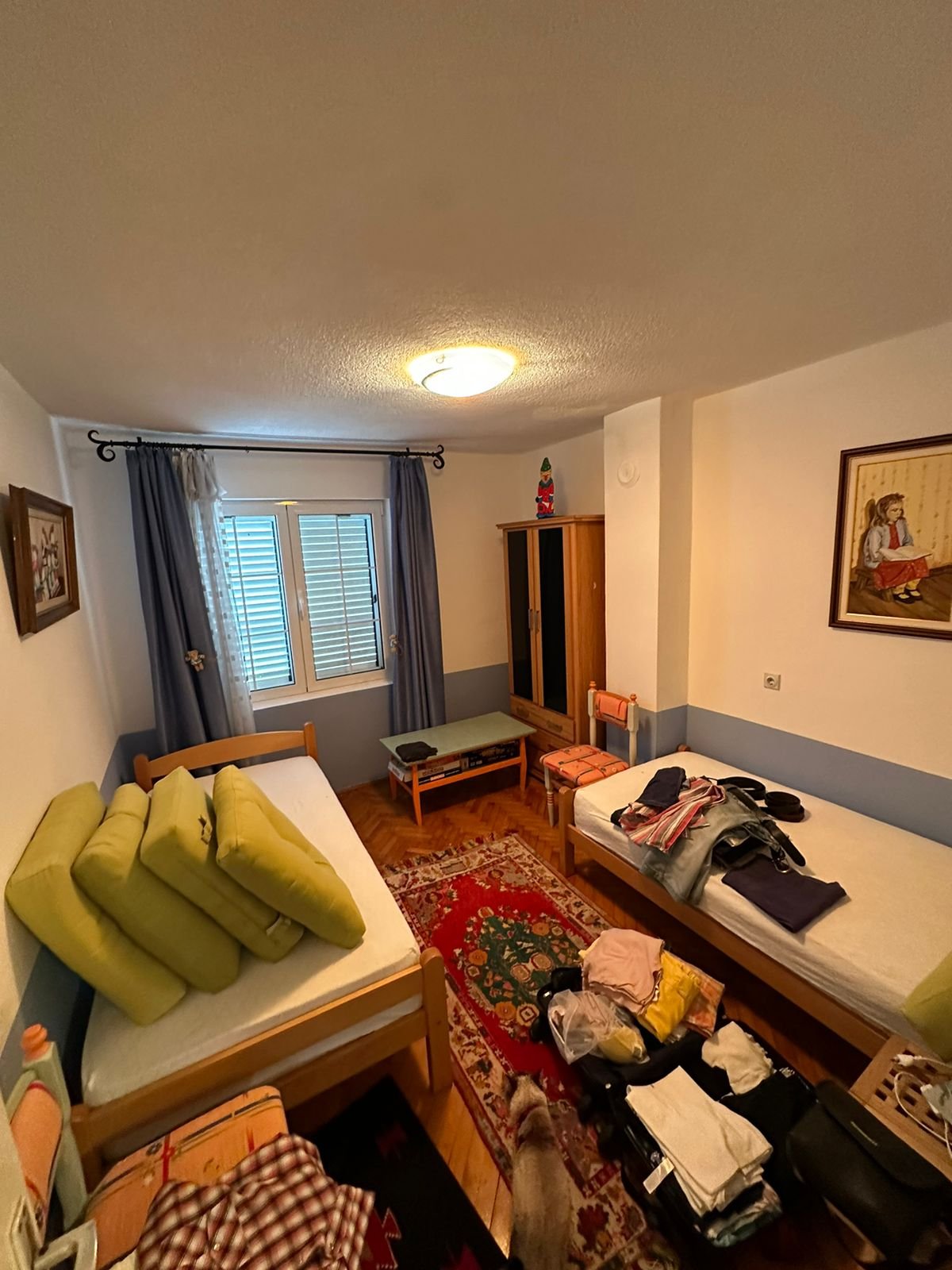 Charming Ulcinj bedroom with 2 single beds, wardrobe, red rug, blue curtains&mdash;ideal Montenegro real estate at immorenta.me by Ekosphere DOO.