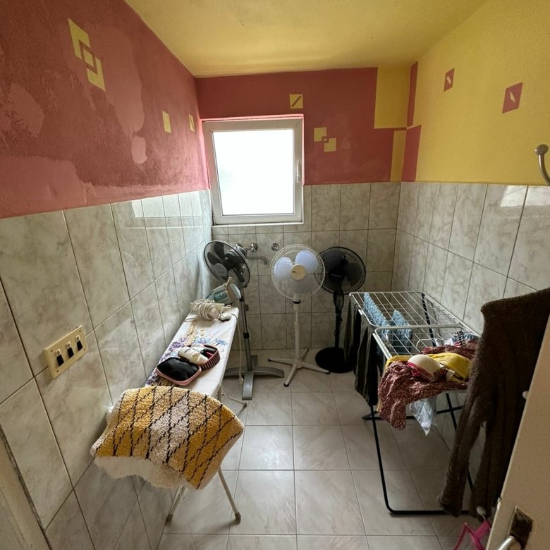 Bright tiled utility room in Ulcinj, Montenegro&mdash;features window, fans, laundry area. Exclusive on immorenta.me by Ekosphere.