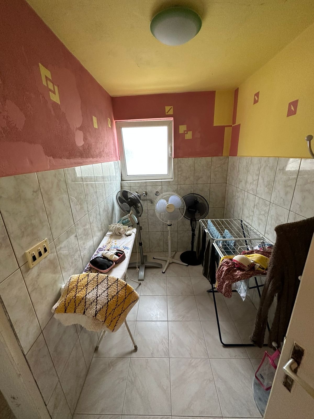 Bright tiled utility room in Ulcinj, Montenegro&mdash;features window, fans, laundry area. Exclusive on immorenta.me by Ekosphere.