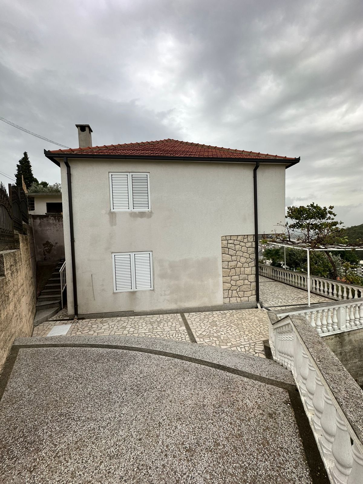 Exclusive Ulcinj property: two-story home with red-tiled roof, white walls, stone terraces. Listed on immorenta.me by Eksphere.