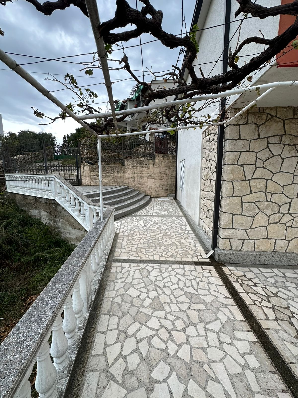 Charming stone house in Ulcinj, Montenegro with stone walls, walkway, and vine trellis&mdash;exclusive at immorenta.me by Ekosphere DOO.