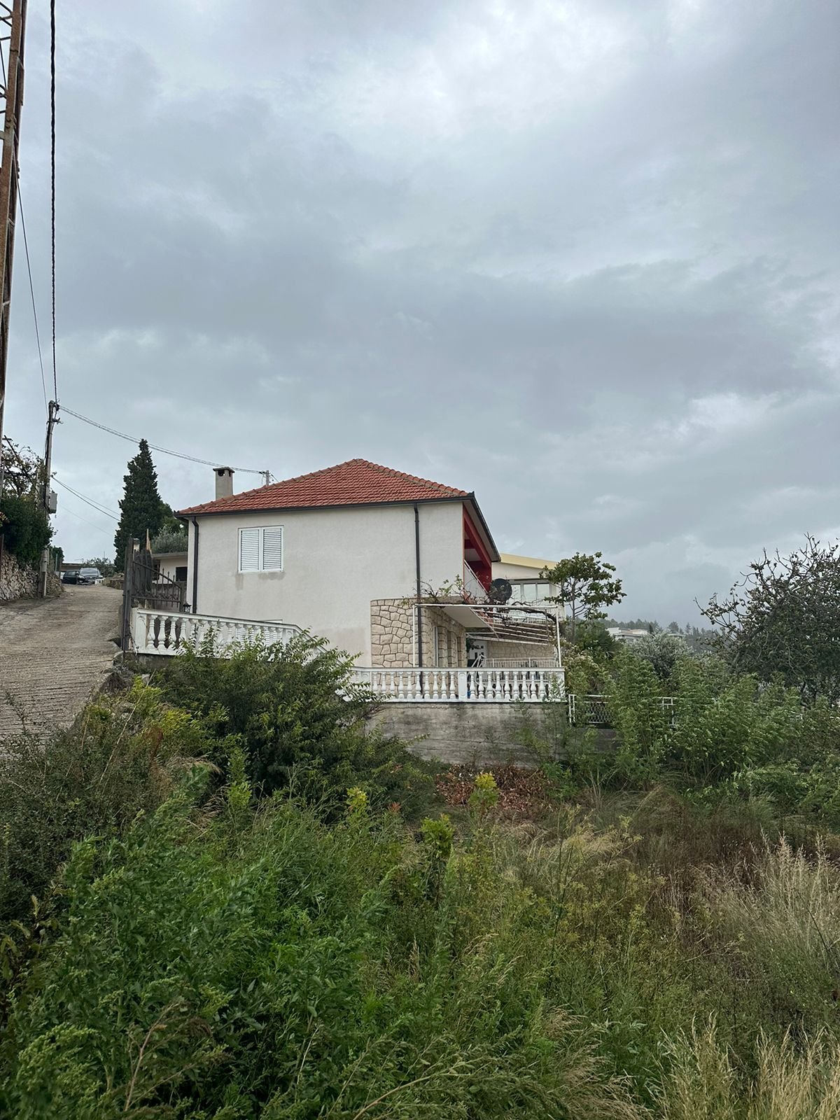 Exclusive two-story home with red roof, lush greenery, and stone balustrade in Ulcinj&mdash;prime investment via immorenta.me.