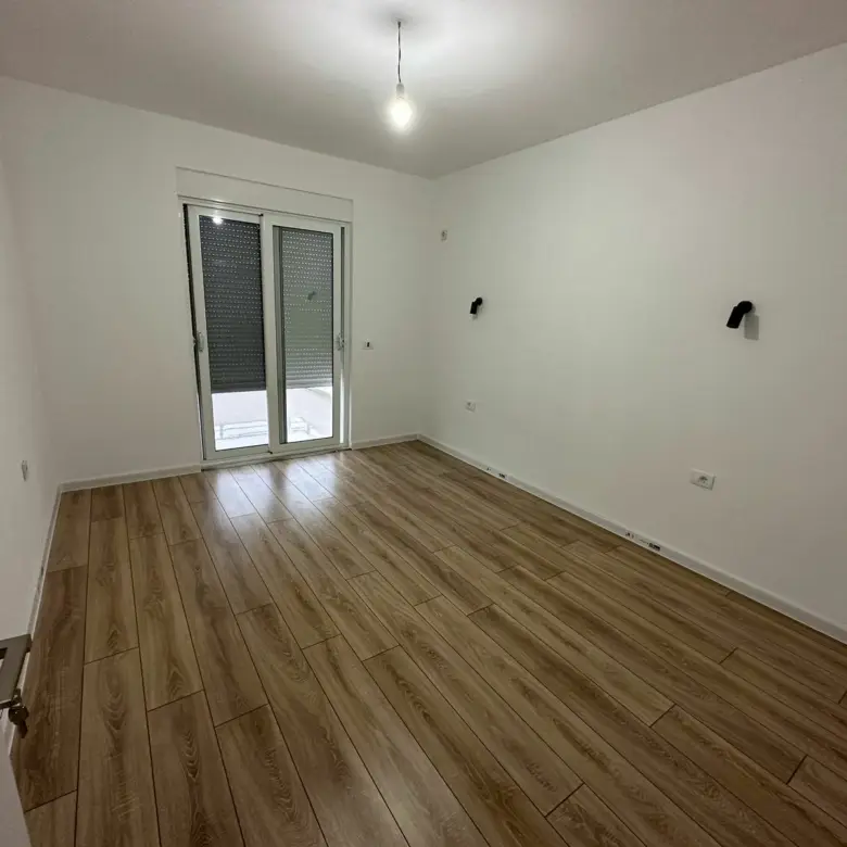 Modern Ulcinj Montenegro property: bright room, wood floors, glass door to outdoors. Featured on immorenta.me by Ekosphere DOO.