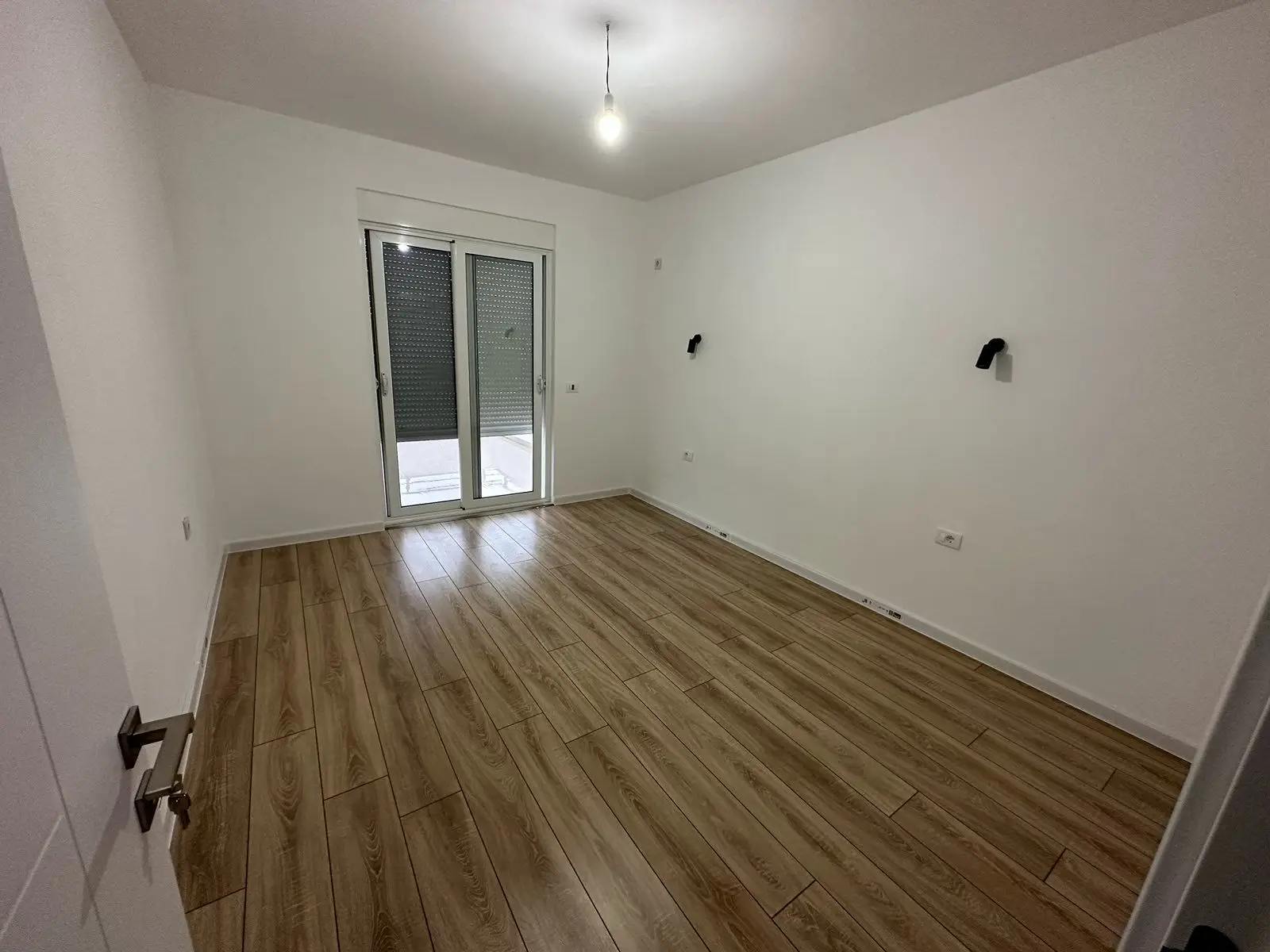 Modern Ulcinj Montenegro property: bright room, wood floors, glass door to outdoors. Featured on immorenta.me by Ekosphere DOO.