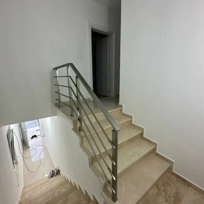 Modern staircase with beige steps, metal handrail, and bright white walls&mdash;ideal Ulcinj real estate by ekosphere doo. Invest today!.