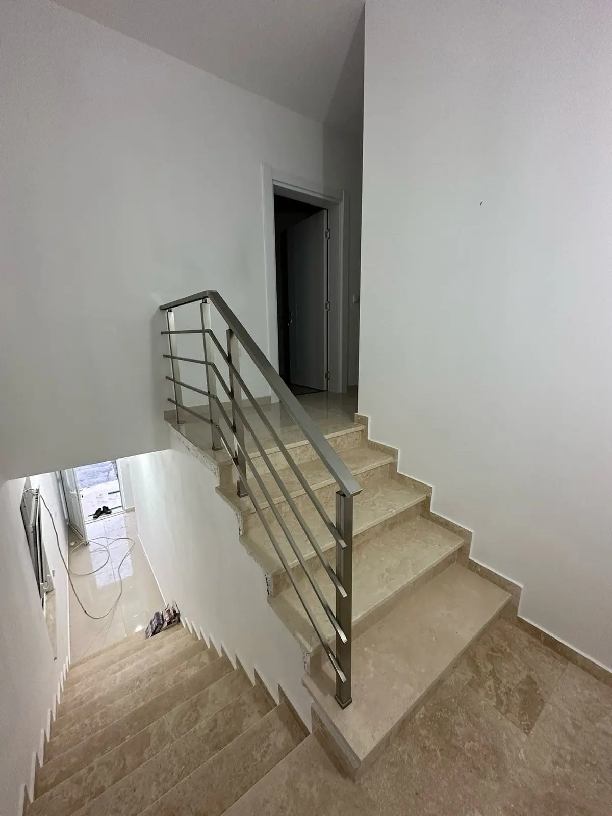 Modern staircase with beige steps, metal handrail, and bright white walls&mdash;ideal Ulcinj real estate by ekosphere doo. Invest today!.